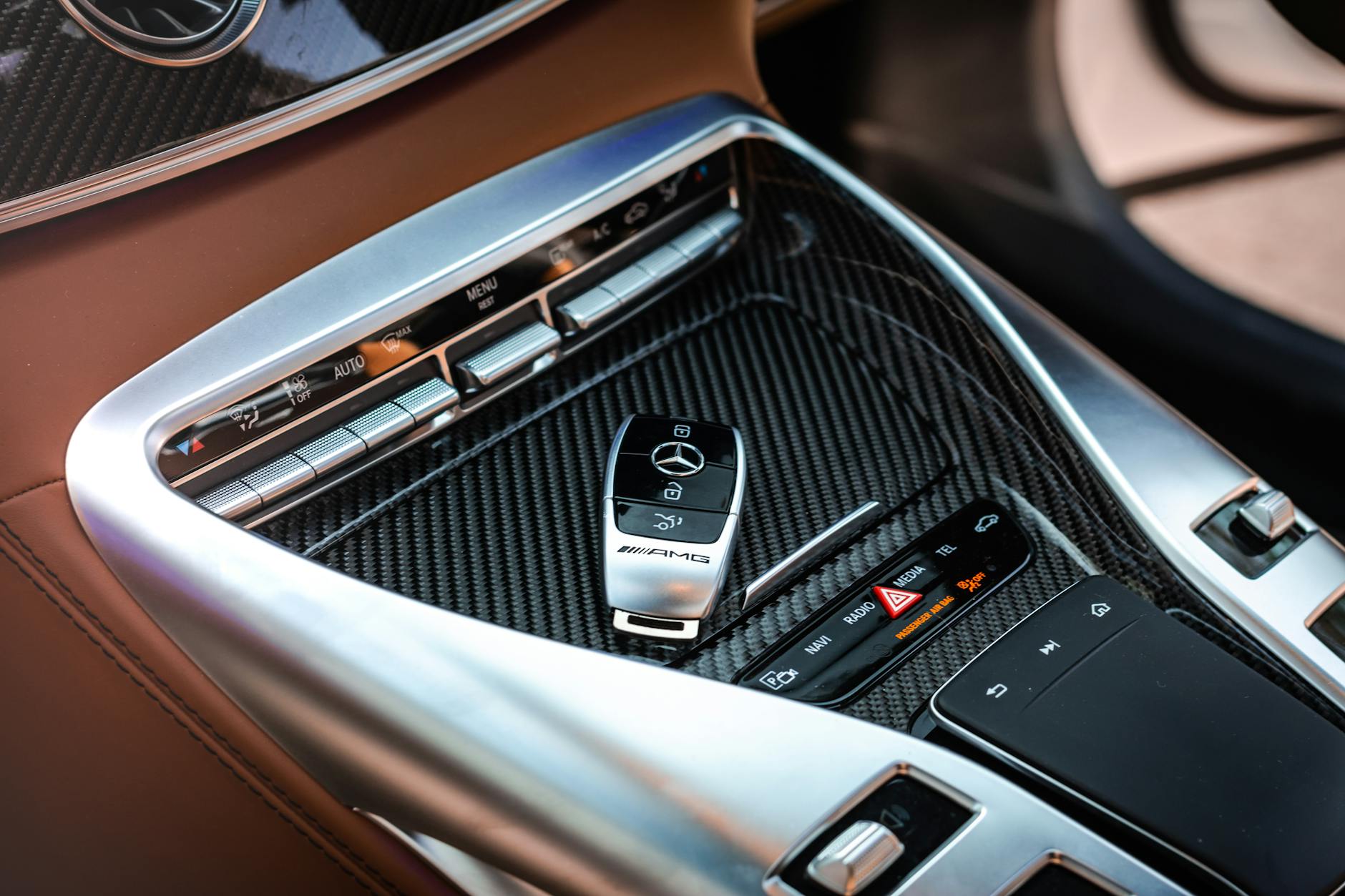 Close-up view of a luxury car's control panel featuring carbon fiber and chrome details with a key fob.