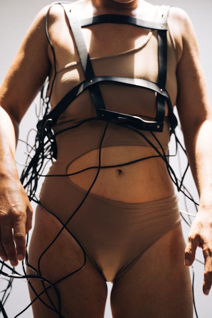 Woman in tech-inspired fashion with cables and harness in modern art style.