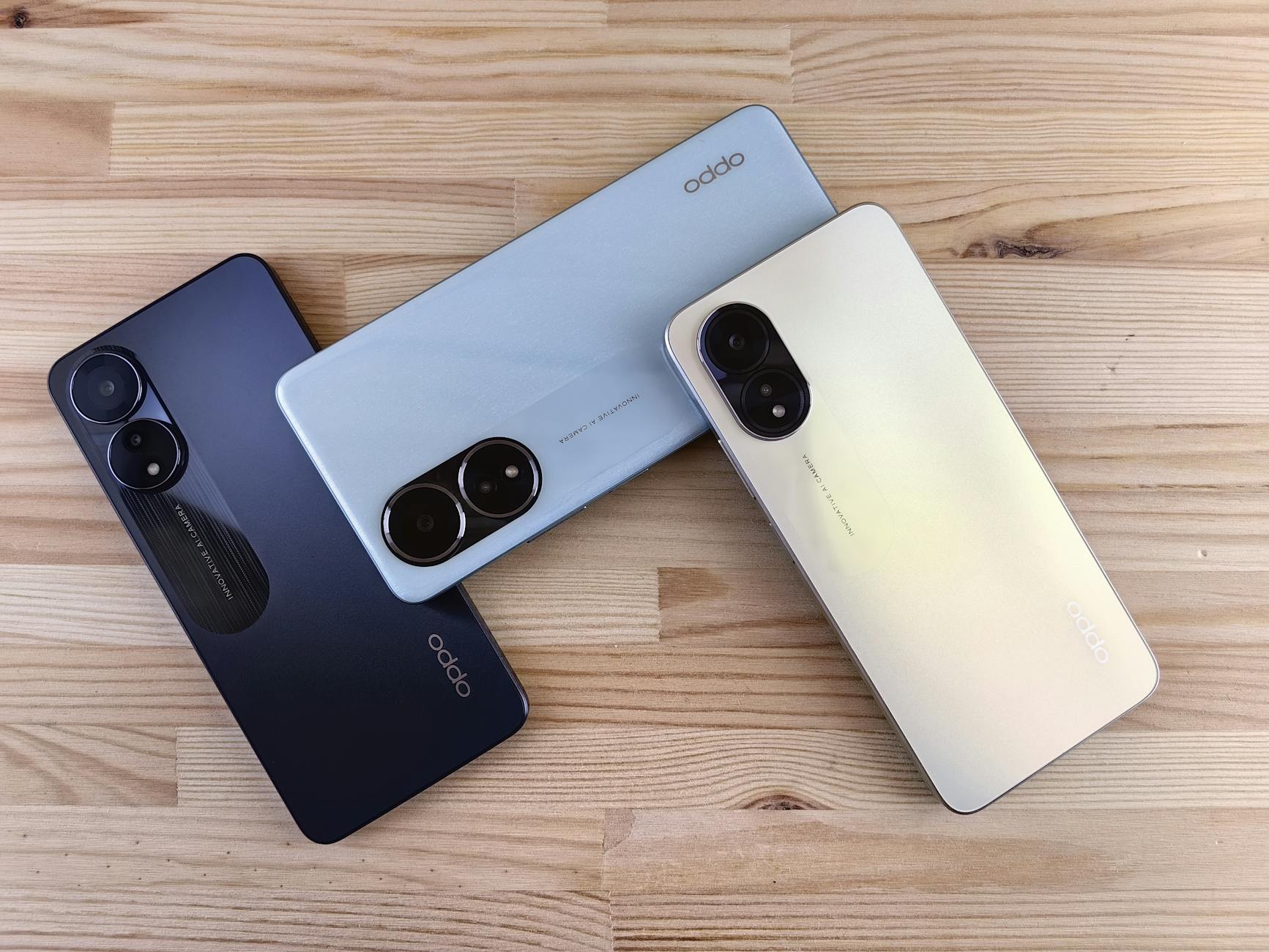 Minimalist flat lay of three smartphones on a wooden surface, showcasing sleek design and camera features.