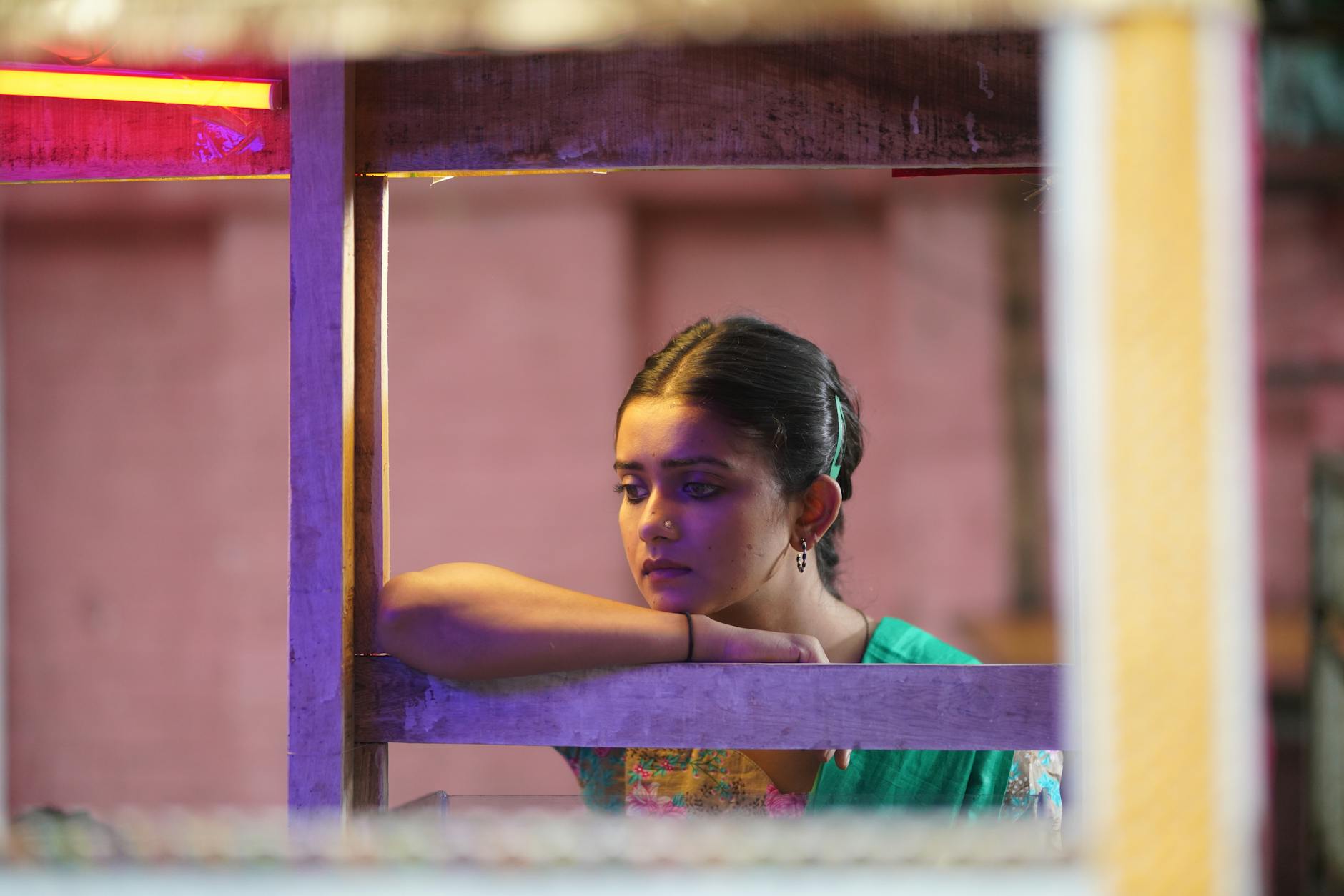 Thoughtful woman looks out from a vibrant street setup in Dhaka, Bangladesh.