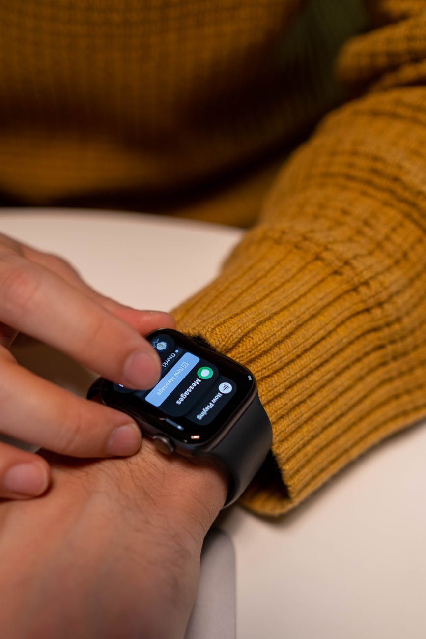 A person wearing a yellow sweater interacts with a smartwatch, focusing on the touch interface.
