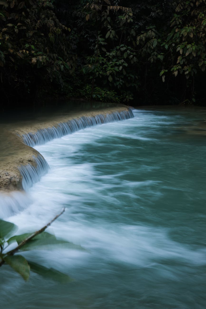 Peaceful waterfall surrounded by dense forest, captured with long exposure for a dreamy effect.